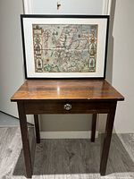 Front view of wooden side table with framed map print resting on top