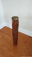 Full view of carved wooden drum standing upright