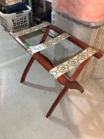 Folding wooden luggage rack standing open, showing decorative straps