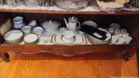 Full set on cabinet shelf showing plates, bowls, tureen, coffee pot, platters, cups, saucers