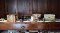 Shelf view showing tins, silver-plated tray, bowl, utensils, cup