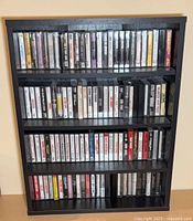 Front view of black wood shelf fully loaded with cassette tapes