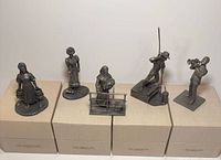 Five pewter figurines on boxes showing titles