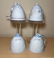 Four Lladro bell ornaments showing dates 2001 and 2006 front, 2000 bells at front