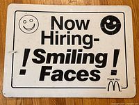 Full view of the McDonald’s “Now Hiring - Smiling Faces!” metal sign showing overall design and wear