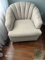 Front view of beige upholstered barrel armchair