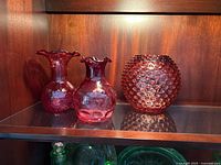 All three cranberry glass pieces on shelf