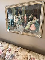 Framed salon concert print hanging above floral sofa