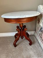 Full view of table showing marble top and wooden pedestal base