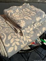 Folded quilt showing blue side with white floral print and quilted stitching