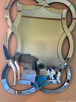 Full view of mirror showing infinity-loop frame and reflective surface