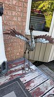 Full view of metal heron sculpture standing on deck