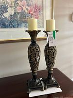 Pair of ornate candle holders with candles on tabletop