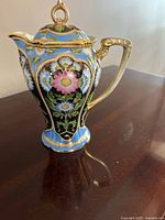 Full view of teapot showing floral panels, blue ground and gilt detailing