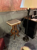 Full view of marble-top wooden accent table beside floor lamp
