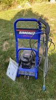 Front view of Simoniz 2000 PSI pressure washer with spray wand and manuals