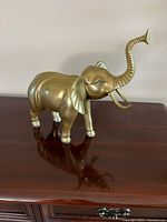 Side view of brass elephant figurine on wooden surface