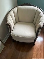 Front view of ivory upholstered armchair showing carved wood frame and seat