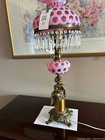 Full view of lamp showing cranberry coin dot shade, prisms, cherub base