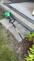 Full view of gas string trimmer lying on ground