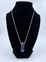 Full view of amethyst pendant necklace displayed on stand