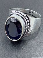 Side view of sterling silver ring showing 925 hallmark and faceted blue sapphire