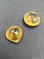 Pair of faceted yellow citrine stones on black background