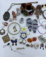 Overview of mixed costume jewelry laid out, showing bracelets, earrings, brooches, rings and pins