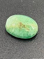 Top view of oval faceted emerald on black background