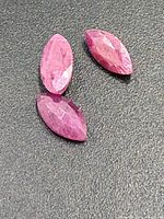 Close-up of three faceted marquise rubies on dark background