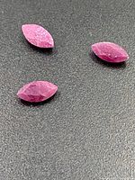 Three marquise-cut rubies on black surface