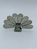 Front view of sterling silver peacock fan fireplace screen fully opened