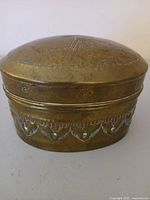 Closed brass box showing lid decoration and patina
