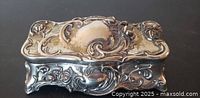 Closed jewelry box front/top view showing ornate rose motif and tarnish spots