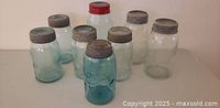 Eight glass canning jars with assorted lids displayed