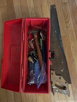 overall view of toolbox filled with tools and separate hand saw