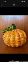 Front view of swirled orange art glass pumpkin with green stem