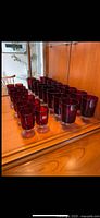 Front view showing entire 14-piece ruby red glass set on wooden surface