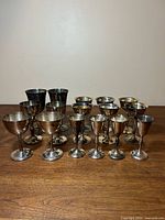 Front view of all 15 silver-plated goblets on wooden surface