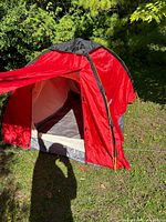 Front and side view of assembled red Toread dome tent outdoors showing overall structure and color