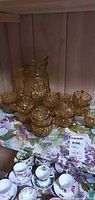 Pitcher and several amber cups displayed on shelf