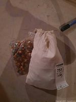 cloth drawstring bag labeled 751 beside plastic bag of marbles