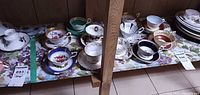 Shelf with multiple teacup and saucer sets, assorted patterns