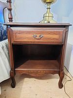 Front view of nightstand showing drawer, open shelf, cabriole legs
