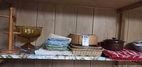 Shelf view showing wood pasta rack, amber glass compote, table linens, wicker placemat and Wedgwood baking dish