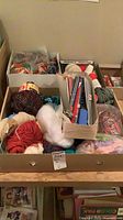 Top view of box showing mixed yarn skeins, knitting needles and hooks