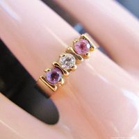 Close-up of ring showing three gemstones and gold setting