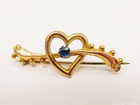 Front view showing heart, blue stone, beaded bar, overall design