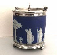 Front view showing blue jasperware body, white classical figures, silver-plated lid and feet