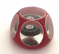 Side view of red overlay faceted paperweight showing three oval windows and millefiori center